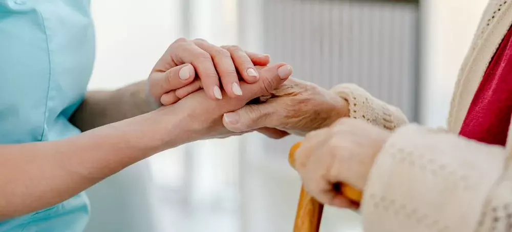 /article/nurses-hand-holding-elderly-womans-hand.webp